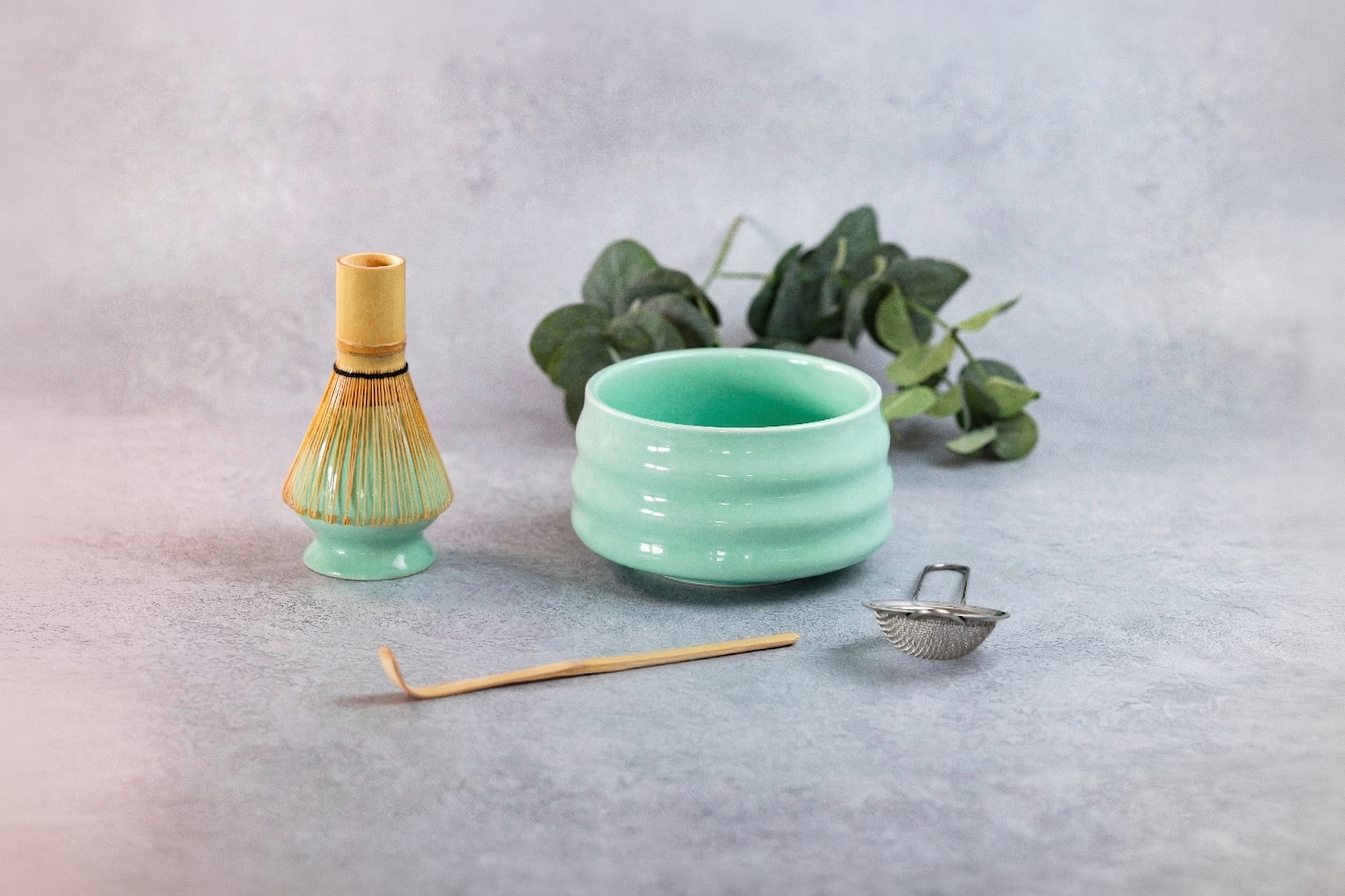 Teal ceramic matcha tea set with accessories on a light gray background