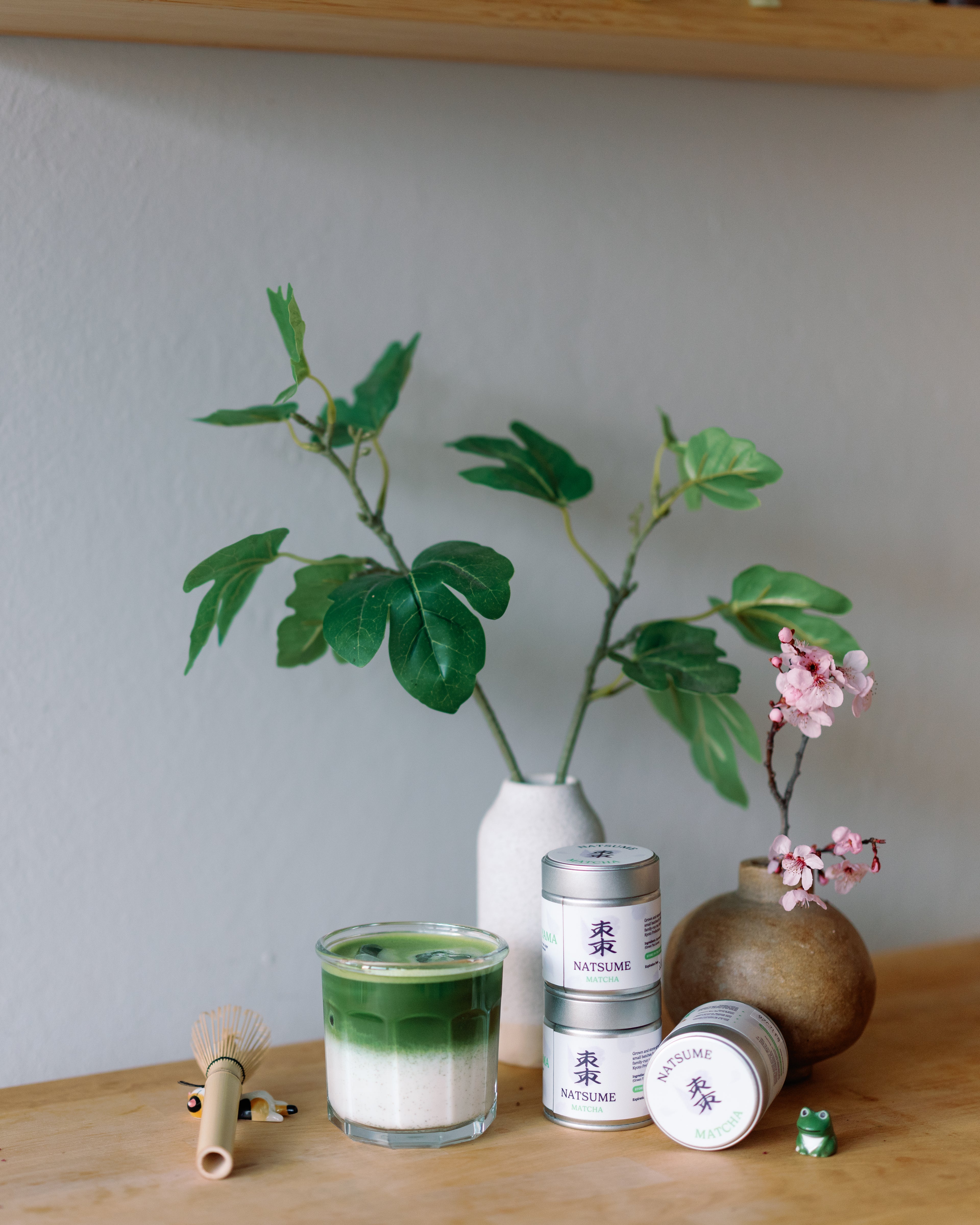 Iced matcha latter with a plant and decorative items on a wooden surface