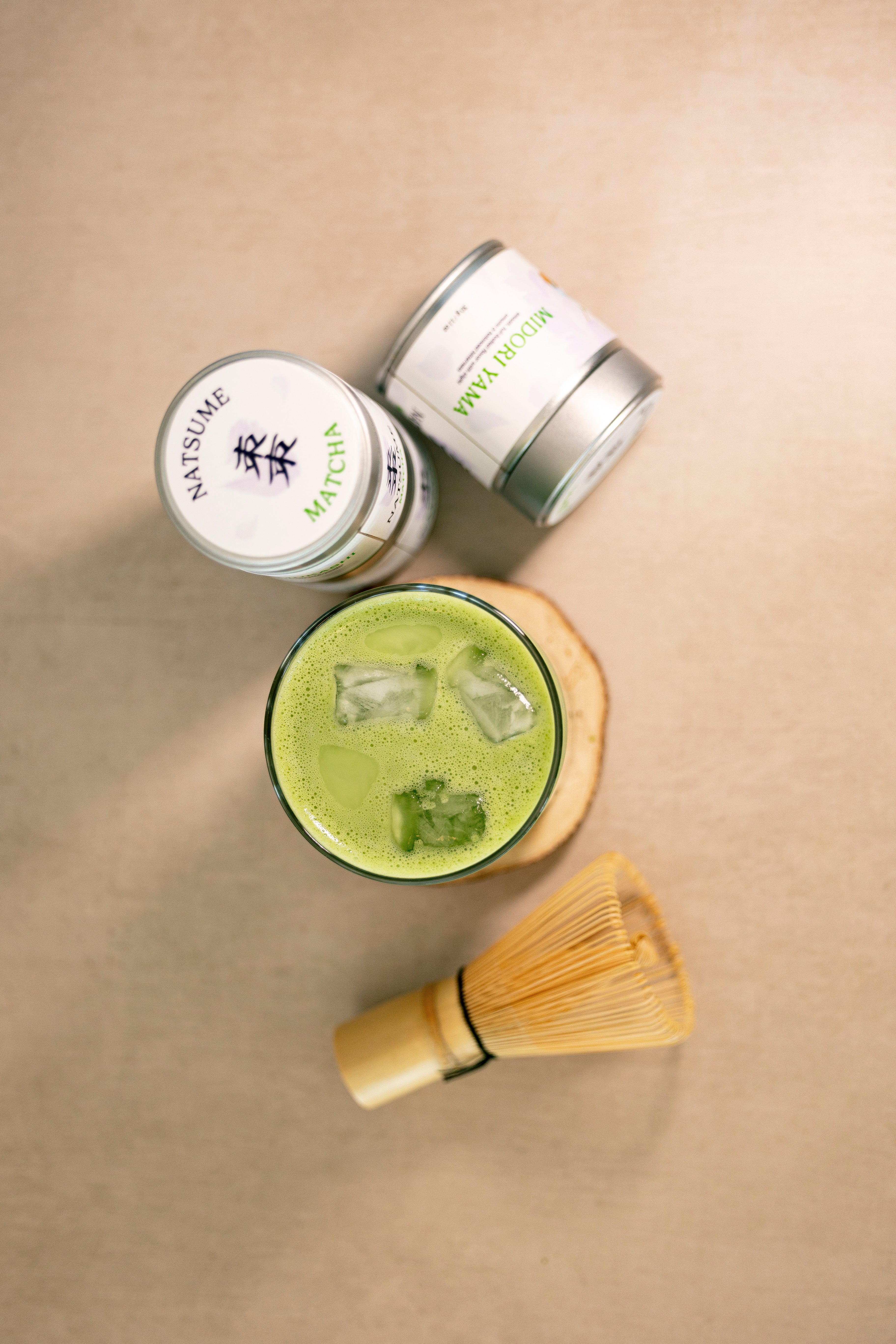 Green iced matcha latte overhead flatly with Natsume Matcha and whisk