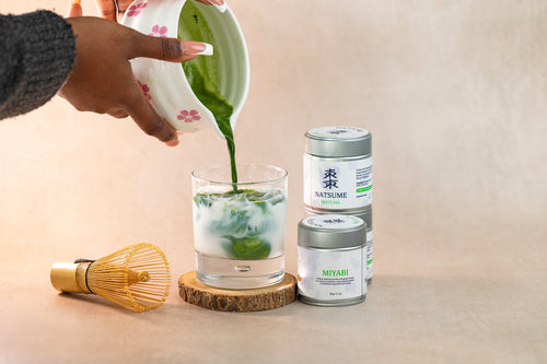 Person pouring green liquid into a glass of milk with Natsume matchas featured on the side and a matcha whisk