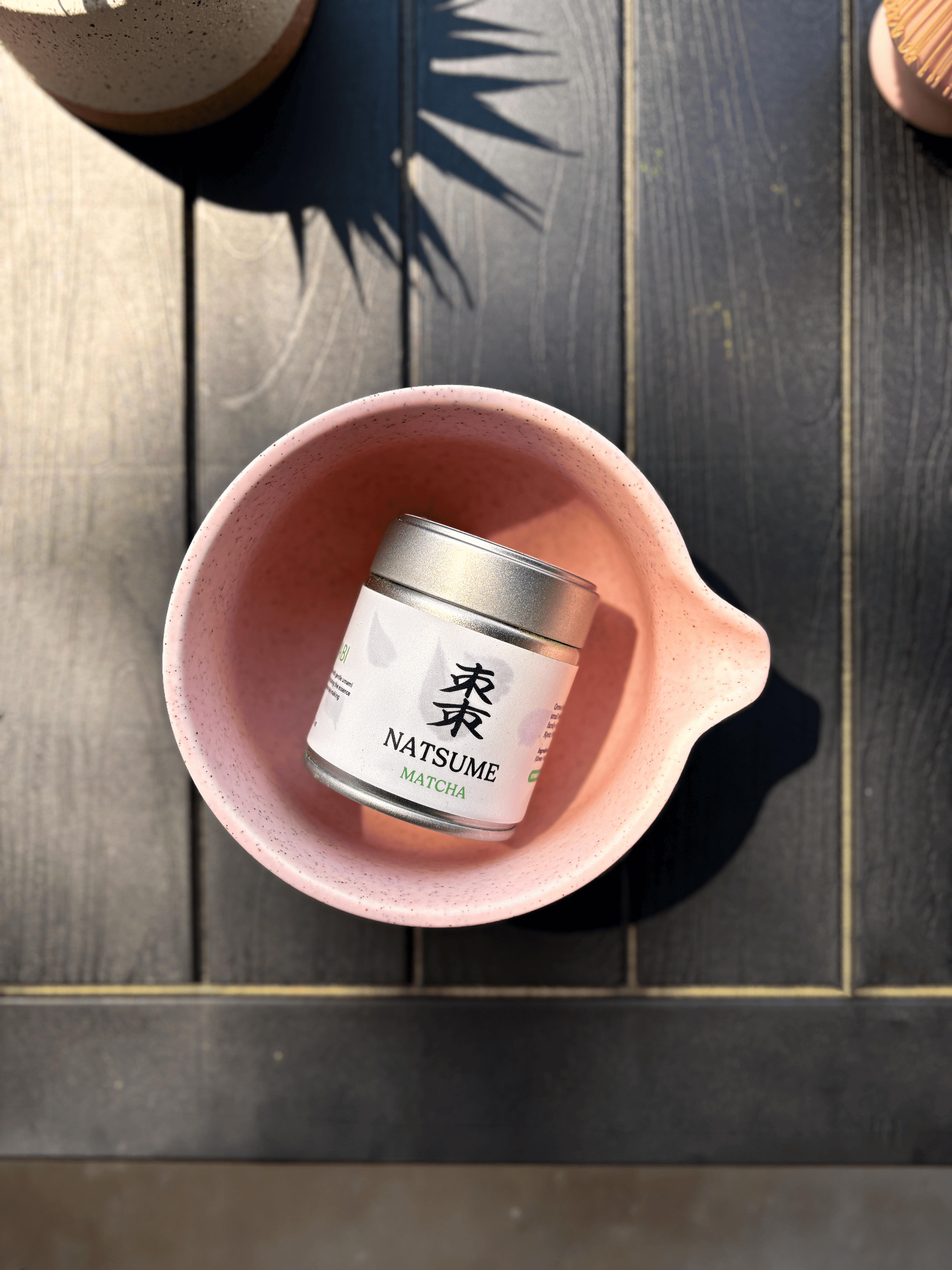 Close-up of a pink matcha bowl and bamboo scoop.